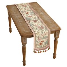 a wooden table with an embroidered runner on it's edge and tassels at the top