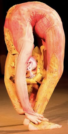 a woman in yellow and pink is bending over with her hands on the ground as she bends down