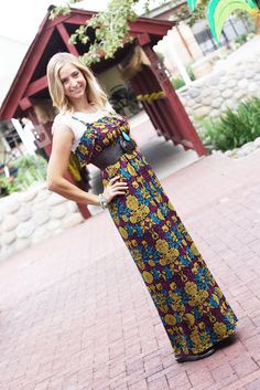 a woman standing in front of a building wearing a long dress with flowers on it