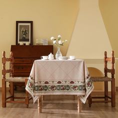 a dining room table with two chairs and a white table cloth on top of it