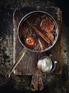 a metal pan filled with food on top of a wooden cutting board next to utensils