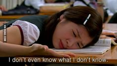 a woman laying on top of a wooden desk next to a book with her eyes closed