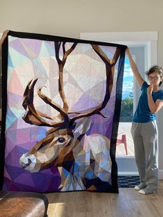 a woman standing next to a large quilt with an image of a deer on it