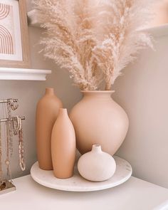 some vases and other decorative items on a white shelf in the corner of a room