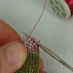 a person is working with some thread on a piece of cloth and the needle has been hooked up to it