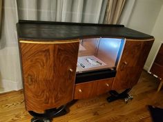 a wooden cabinet with an open door on wheels