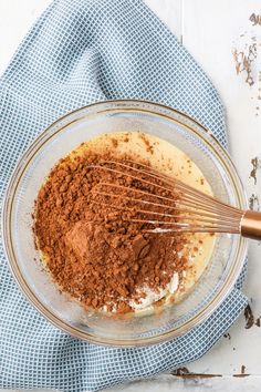 a glass bowl filled with chocolate and whisk on top of a blue towel