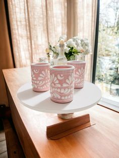 three pink cups sitting on top of a white plate