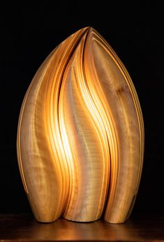 a wooden vase sitting on top of a table next to a black wall and floor