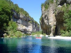 two people in a boat on the water near some cliffs