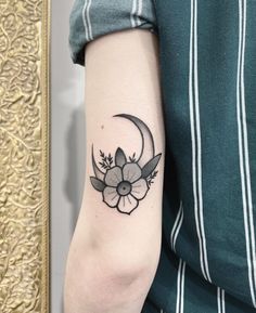 a woman's arm with a flower and crescent tattoo on the left inner arm