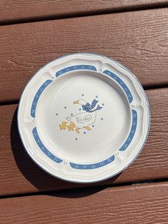 a white and blue plate sitting on top of a wooden table next to a wall