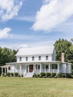 a large white house sitting on top of a lush green field