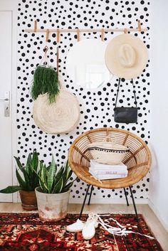 a room with black and white polka dots on the wall, two wicker chairs and a potted plant