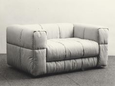 a gray couch sitting on top of a floor next to a white wall with no one in it