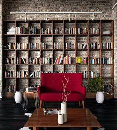 a red couch sitting in front of a book shelf filled with books