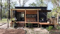 a small house with lots of plants on the front porch and steps leading up to it