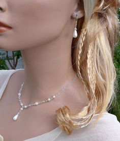 a mannequin head wearing a necklace and earring with pearls on the neck