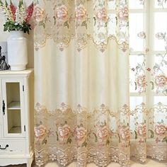 the curtains in this room are decorated with pink flowers and lace, along with a white cabinet