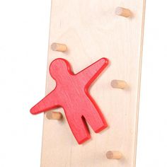 a wooden toy with a red stick figure on it's side and pegs in the background