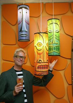 a man standing in front of a wall with two lamps hanging from it's sides