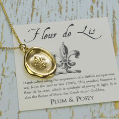 a gold wax seal necklace with fleur de lis written in french on it