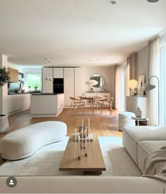 a living room filled with furniture next to a kitchen and dining room table on top of a hard wood floor