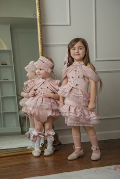 This elegant Pink Satin Ballerina Dress will make any girl feel like a princess! The soft pink lace and cascading ruffles of tulle create a delicate and feminine look, while the emerald green jewel embroidery adds a touch of glamour. Perfect for special occasions and dress-up play, this dress will surely inspire joy and imagination in your little one. Soft pink satin and delicate cotton lining for comfort Fit is true to size and above the knee Back zipper closure Lace, tulle and beading embellishments Draped sleeves add touch of elegance and sophistication Made in Turkey Matching sister romper available! 100% Polyester, 100% cotton lining Care Instructions: Do not wash. Dry clean only. Jewel Embroidery, Ballerina Hair, Matching Sisters, Draped Sleeves, Girls Dress Outfits, Sisters Dress, Ballerina Dress, Baby Boy Hats, Knitted Booties