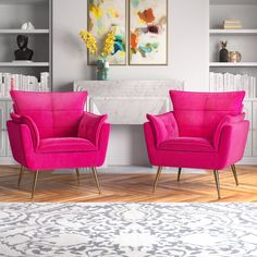 two pink chairs sitting in front of a fireplace