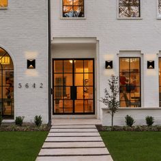 a white brick house with large windows and steps leading up to the front door area