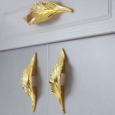 two gold leaves are hanging on the wall next to a white door and some hooks