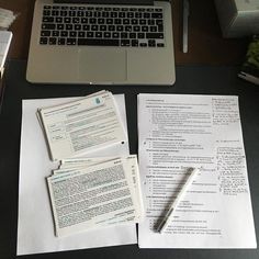 a laptop computer sitting on top of a desk next to papers