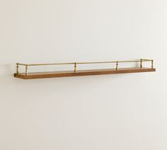 a wooden shelf with metal bars on the top and bottom, against a white wall