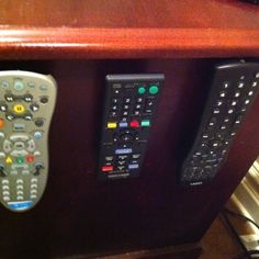 two remote controls are attached to the side of a wooden cabinet with text that reads, 5 use velcro to keep your remotes in place