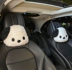 two stuffed panda bears sitting in the back seat of a car with black and white seats