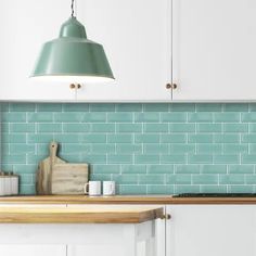 a kitchen with blue tiles on the backsplash and wooden counter tops, along with white cabinets