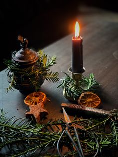 a lit candle sitting on top of a wooden table next to scissors and orange slices