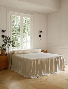 a bed with a white bedspread sitting next to a window