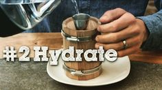 a person pours water into a wooden coffee pot on top of a white plate