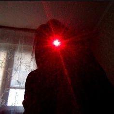 a person standing in front of a window with red light shining on it's face