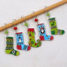 four christmas stockings hanging from a wooden stick on a white surface with a pencil in the foreground