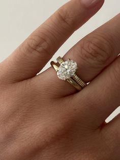 a woman's hand with a diamond ring on top of her finger and an engagement band