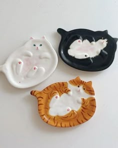 three ceramic cats sitting next to each other