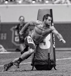 a shirtless man sitting on top of a chair in the middle of a field