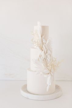 a three tiered white wedding cake with flowers on top