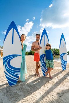 a man and two children are standing on the beach with surfboards in front of them