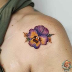 a woman's shoulder with a flower tattoo on the left side of her body