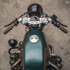 the front end of a green motorcycle parked on top of a cement floor next to a wall