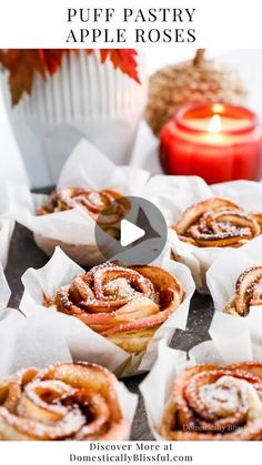 some cinnamon rolls sitting on top of paper next to a candle