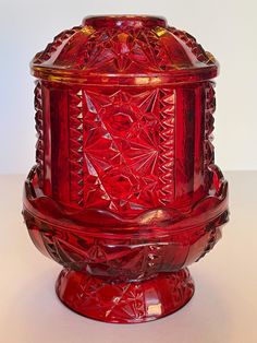 a red glass vase sitting on top of a table